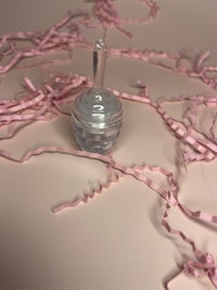 a small glass bottle surrounded by pink ribbons