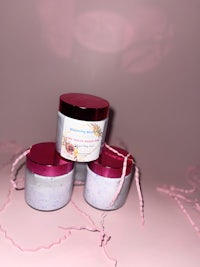 three jars of bath bombs on a pink background