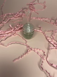 a small glass bottle surrounded by pink ribbons